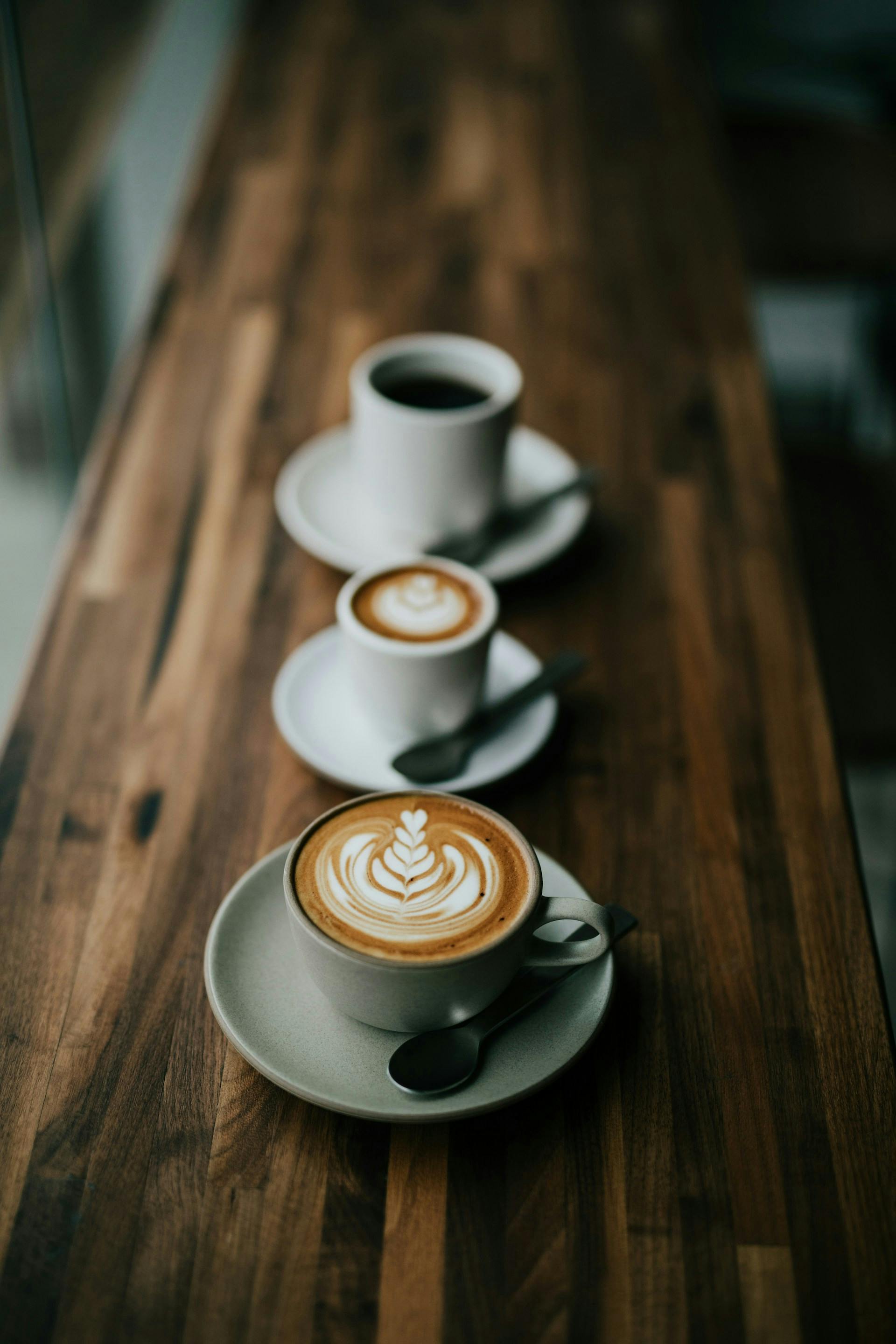 Drei Tassen mit Kaffee auf einem Holztresen 