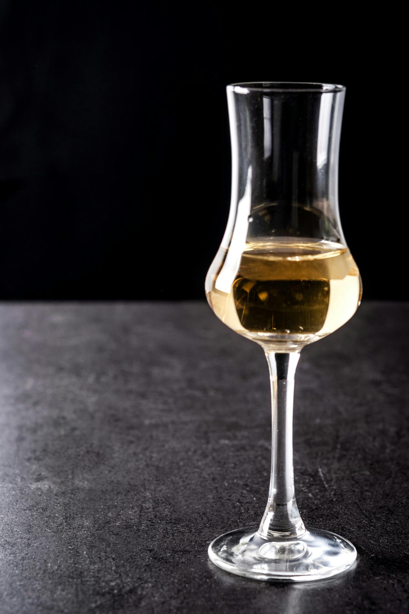 Glas mit gelblicher Flüssigkeit mit dunklem Hintergrund