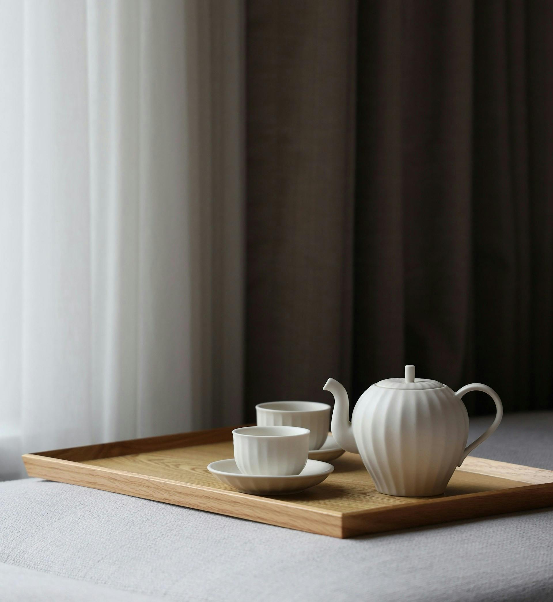 Teekanne und Tassen stehen auf einem Holztablet