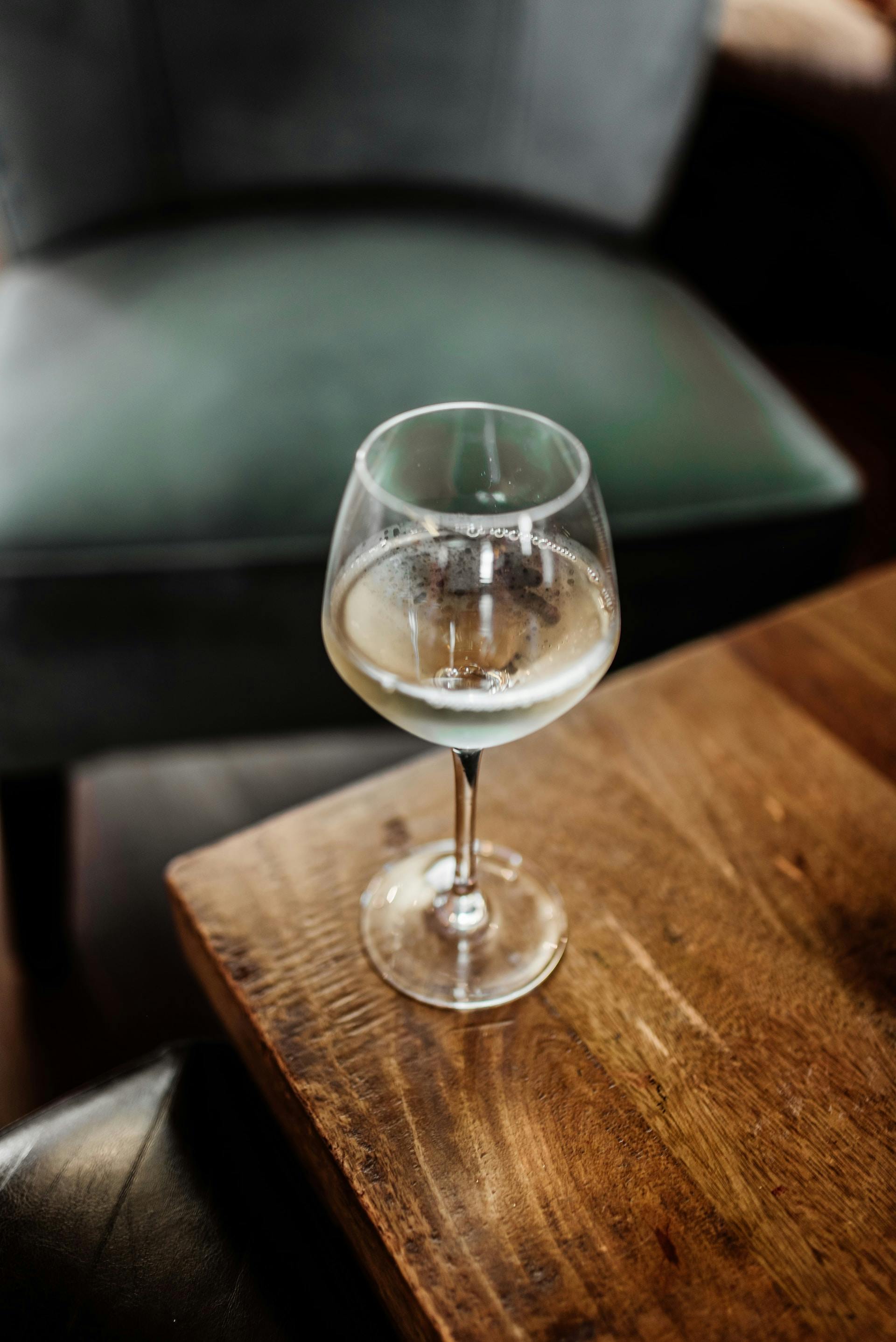 Auf Holztisch Weinglas mit klarer Flüssigkeit