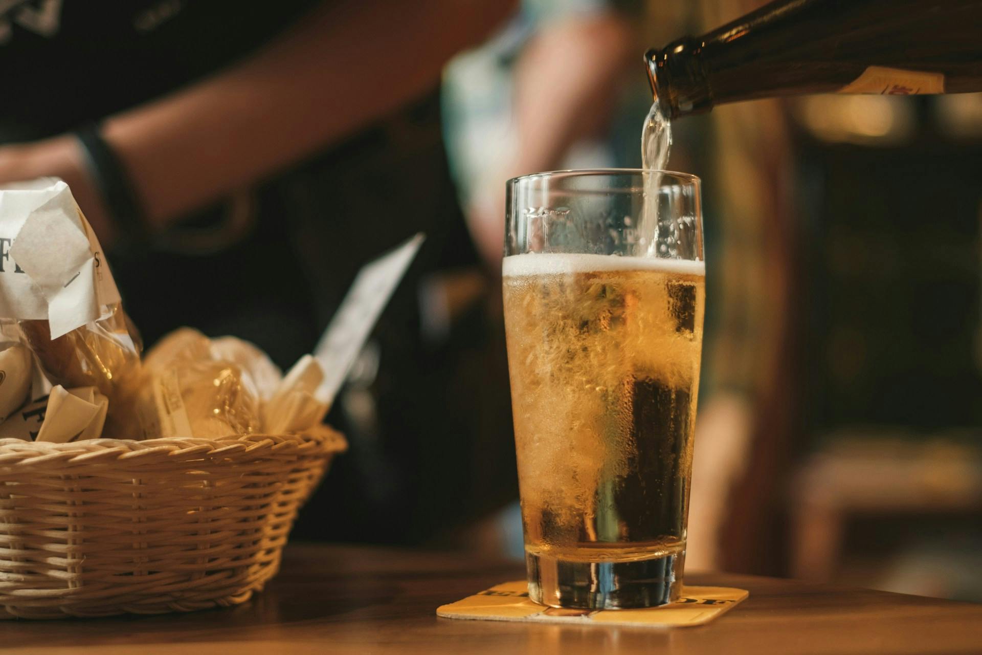 Bier wird aus Flasche in Glas geschenkt 