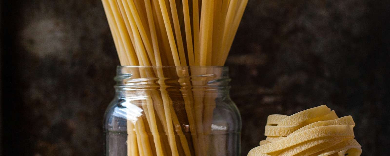Verschiedene Pasta-Sorten in Glas und auf Tisch