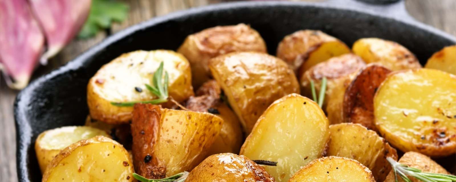 Grobe Bratkartoffeln mit Rosmarin in Pfanne Closeup