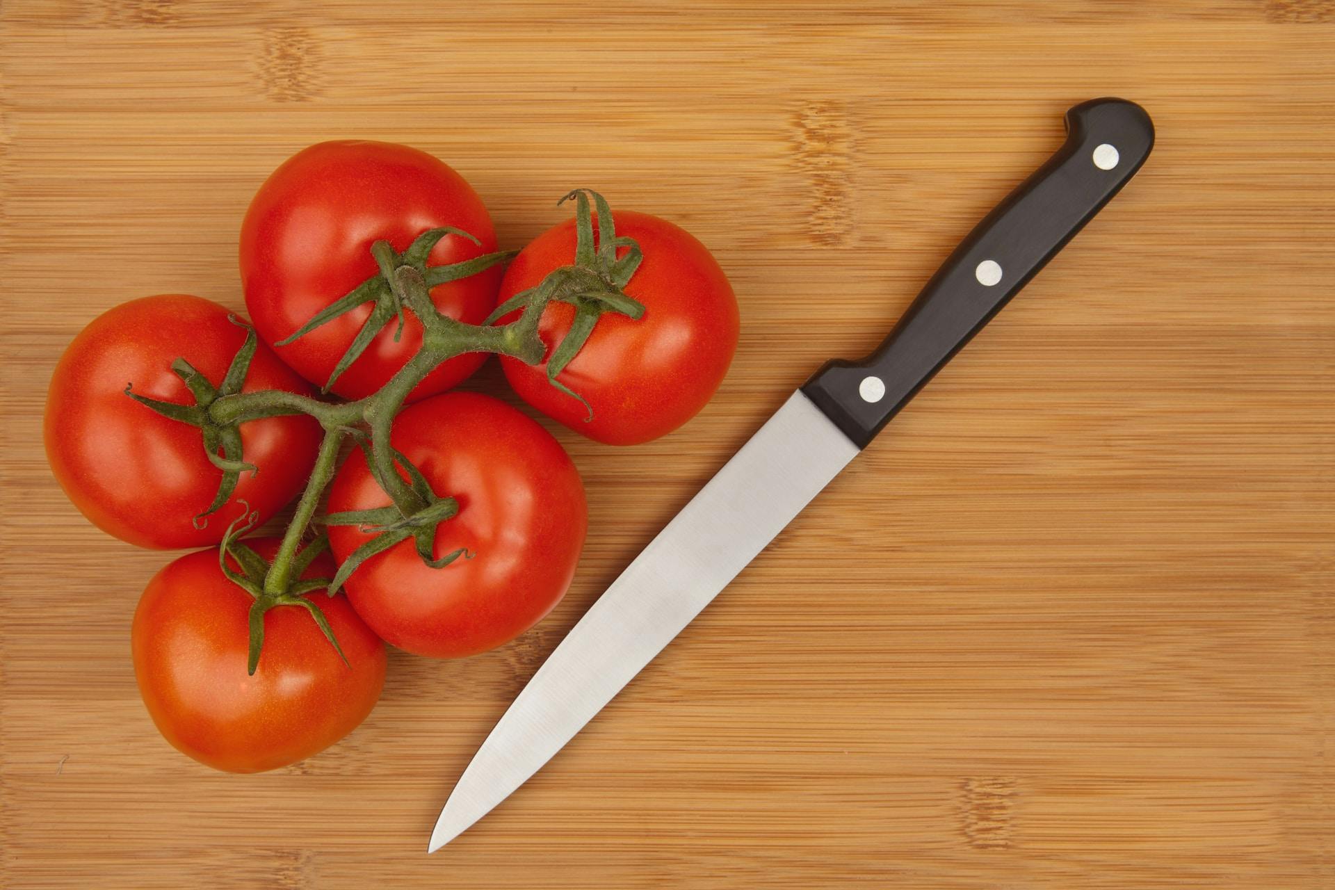 Tomaten und Messer auf Holzschneidebrett 