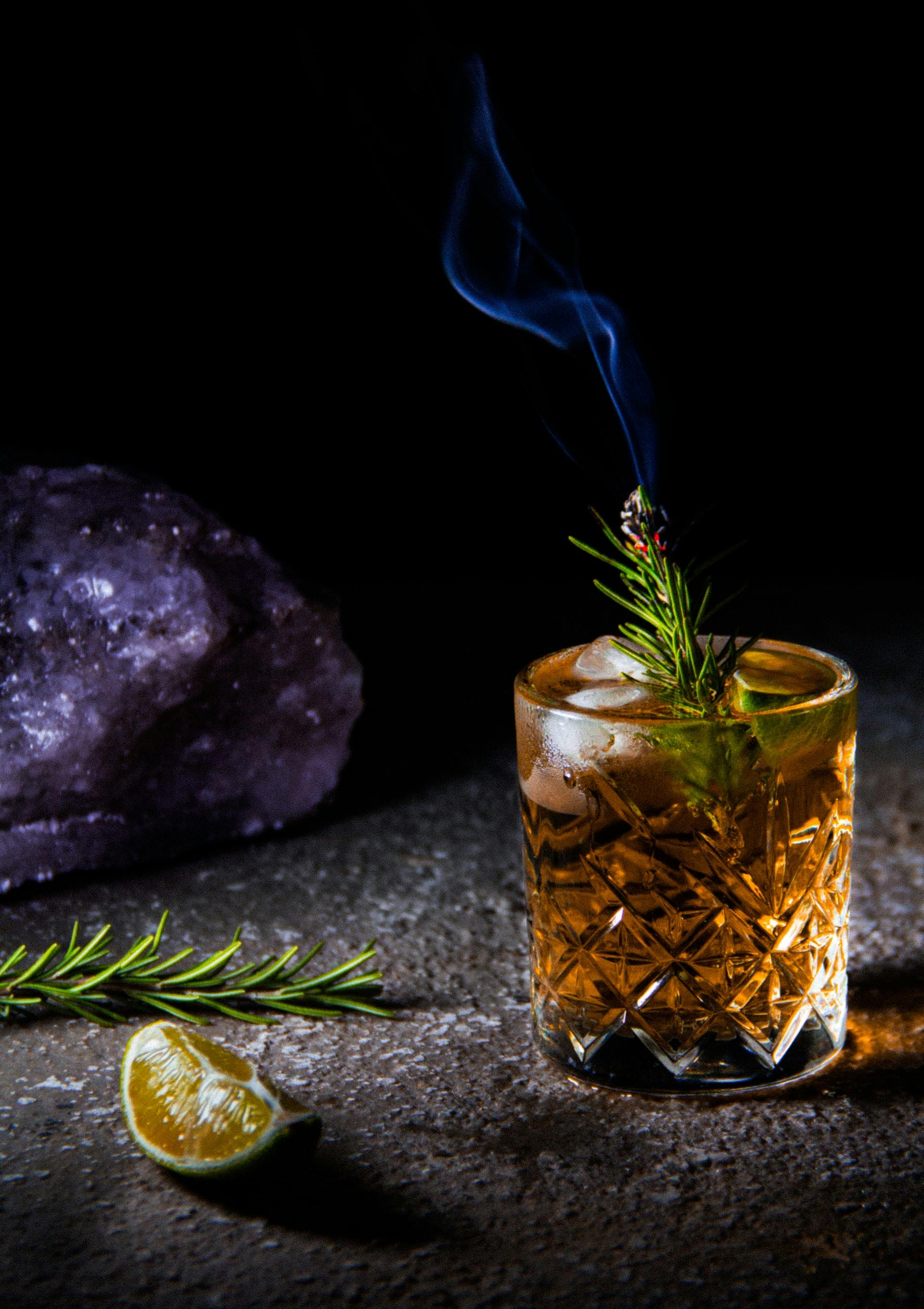 Whisky im Glas mit Rosmarinzweig und Rauch