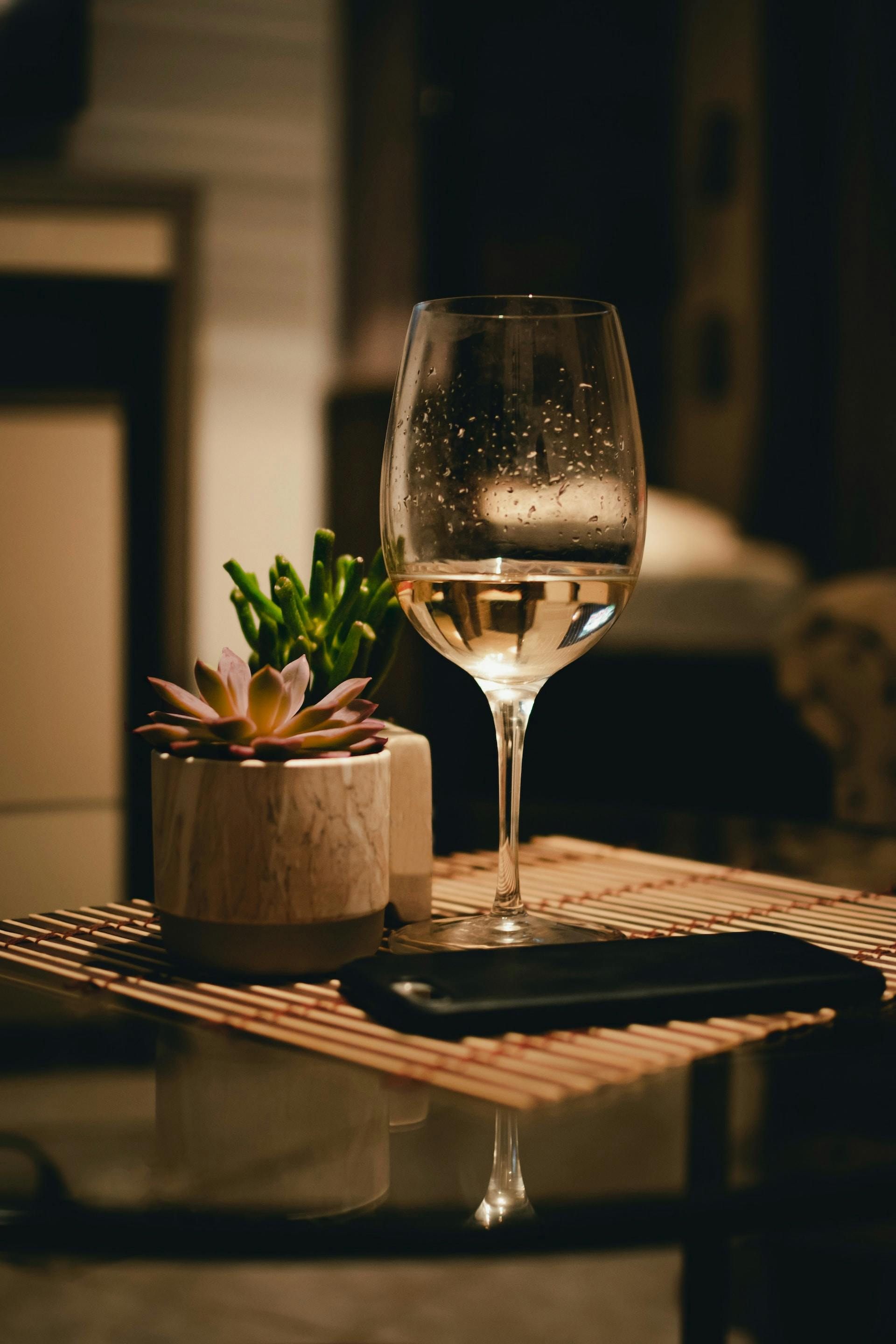 Weinglas mit klarer Flüssigkeit auf Tisch