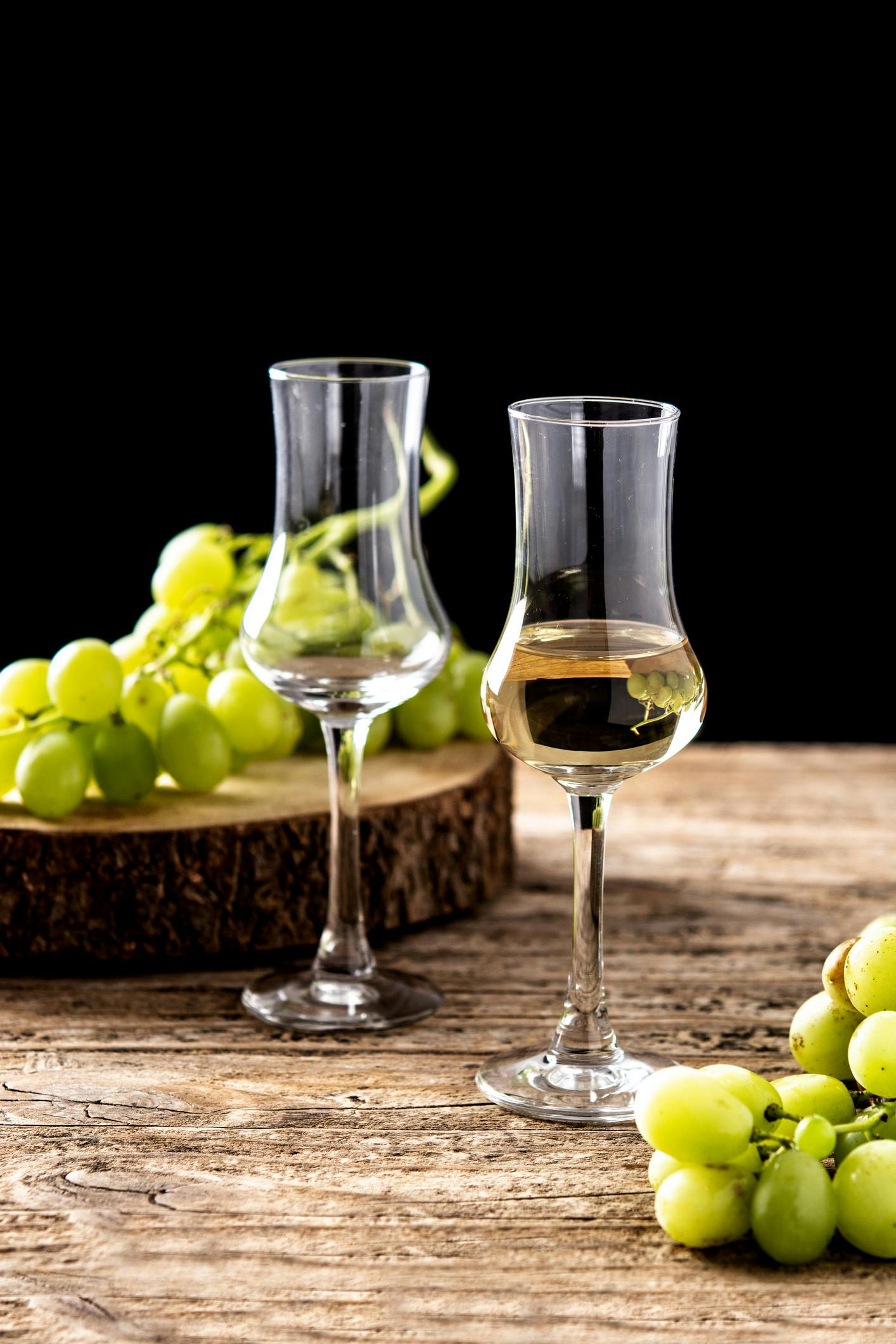 Zwei Grappa Gläser neben grünen Weintrauben