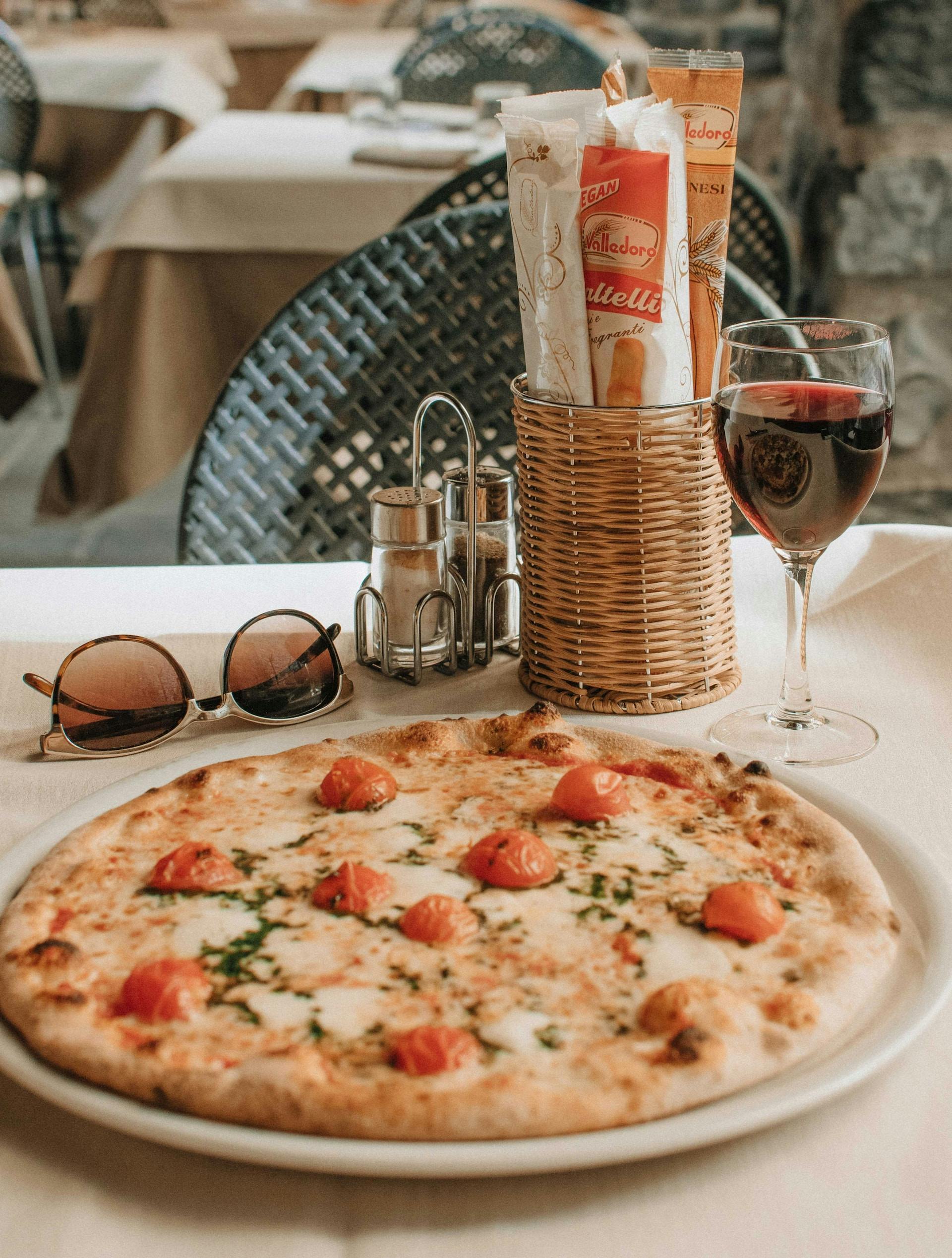Eine Pizza und ein Glas Wein stehen auf einem Tisch 
