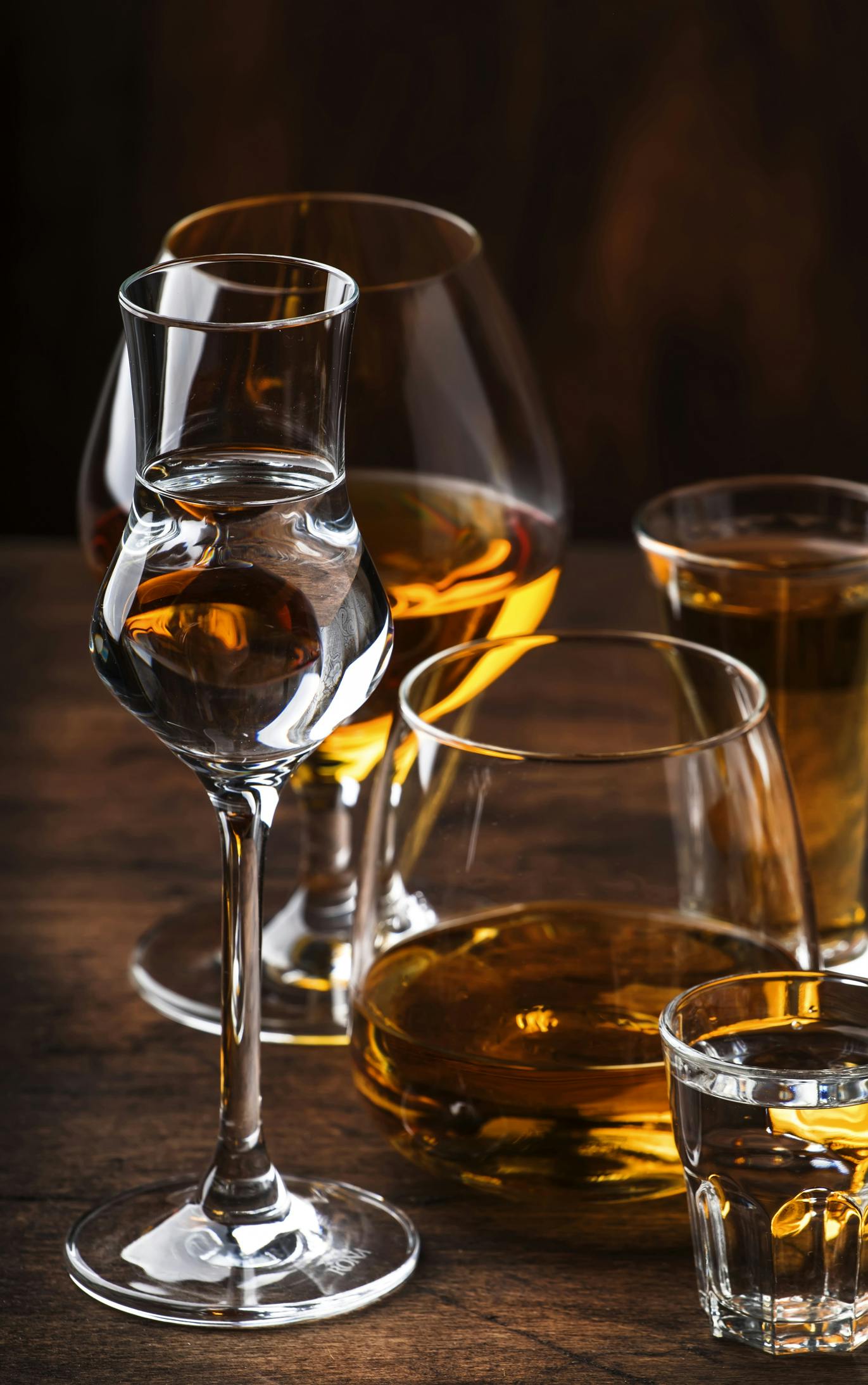 Verschiedene Gläser gefüllt mit alkoholischen Getränken auf einem Holztisch