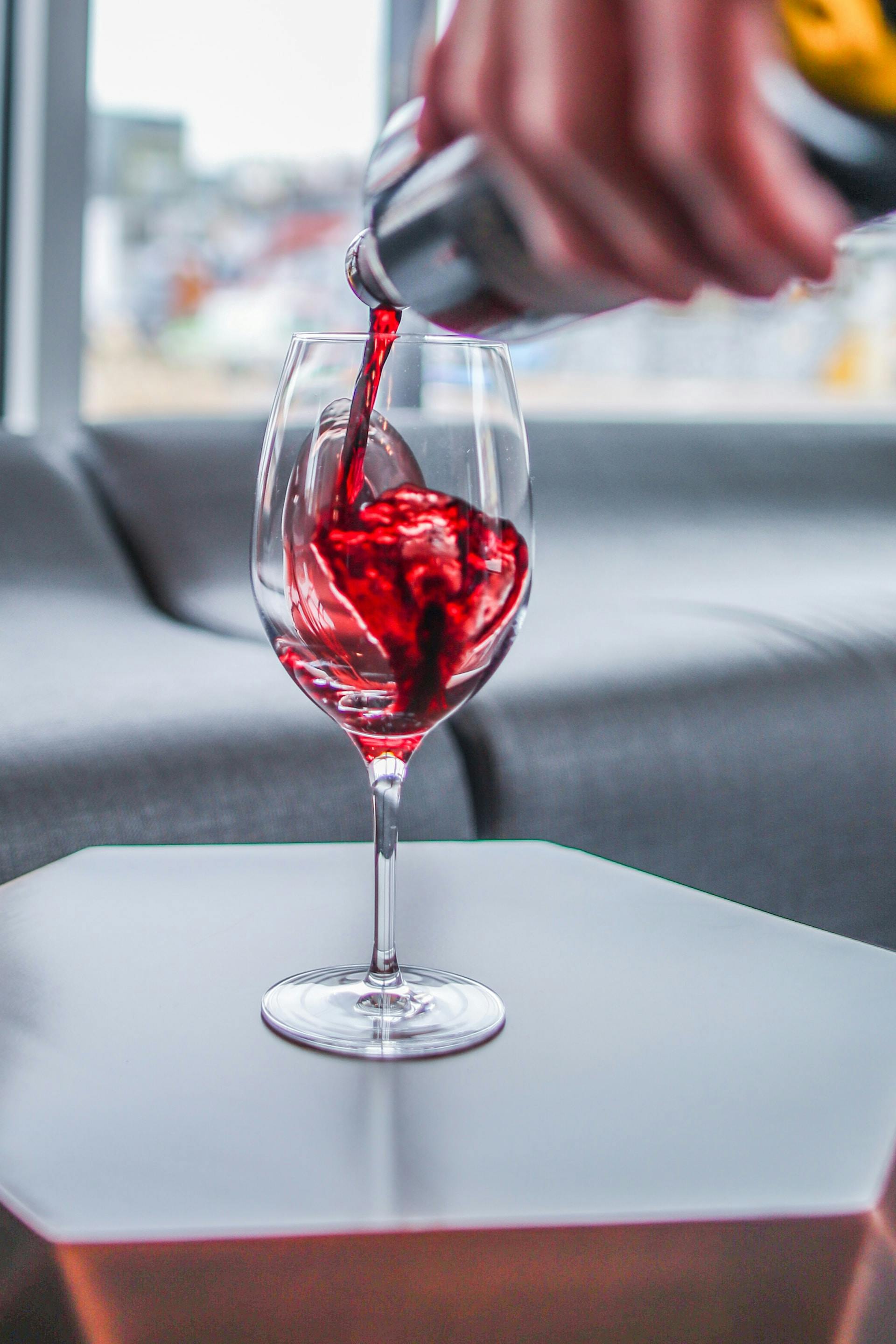 Rote Flüssigkeit aus Weinflasche wird in Weinglas eingefüllt