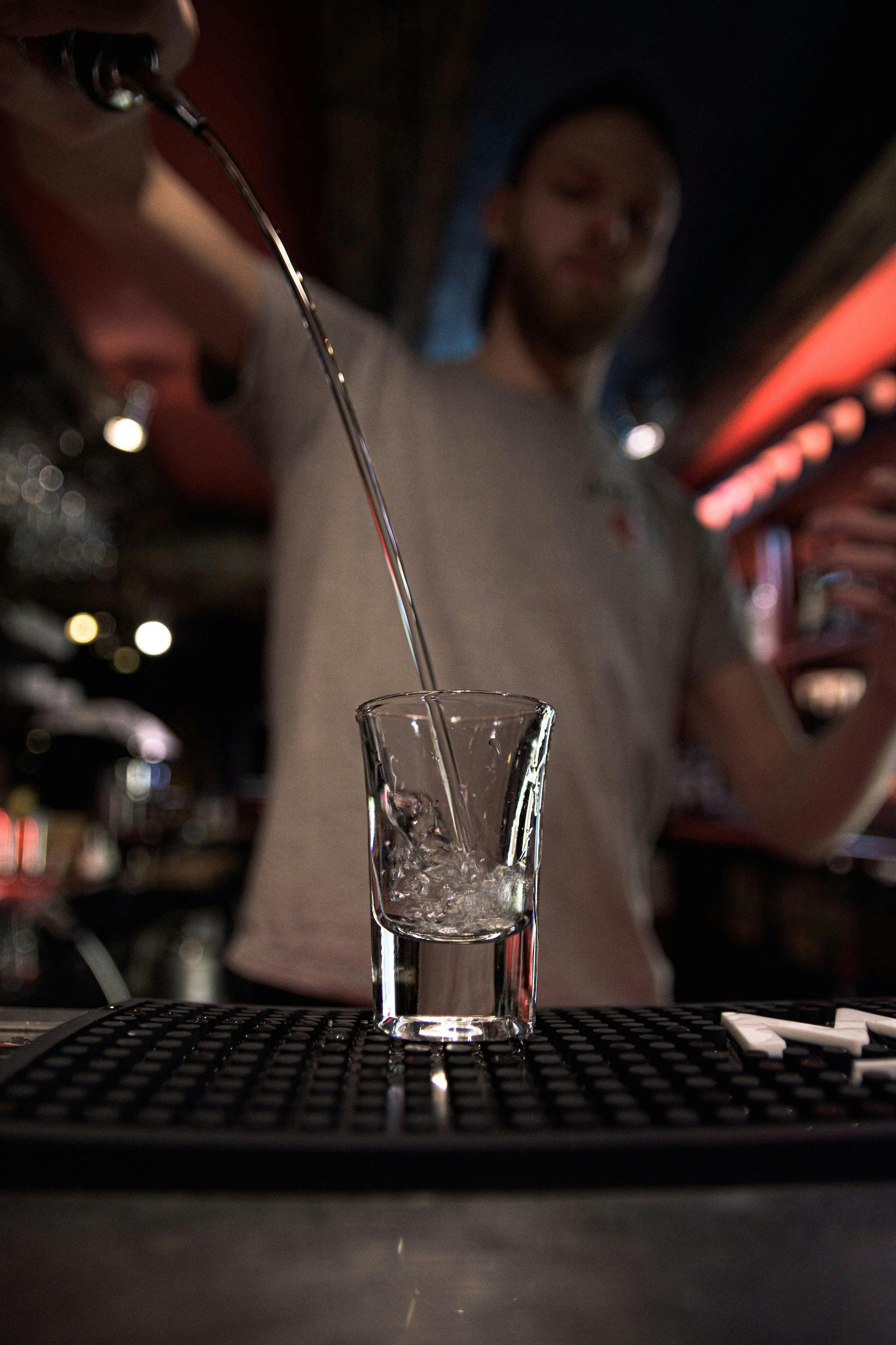 durchsichtige Flüssigkeit wird in Shot Glas geschüttet