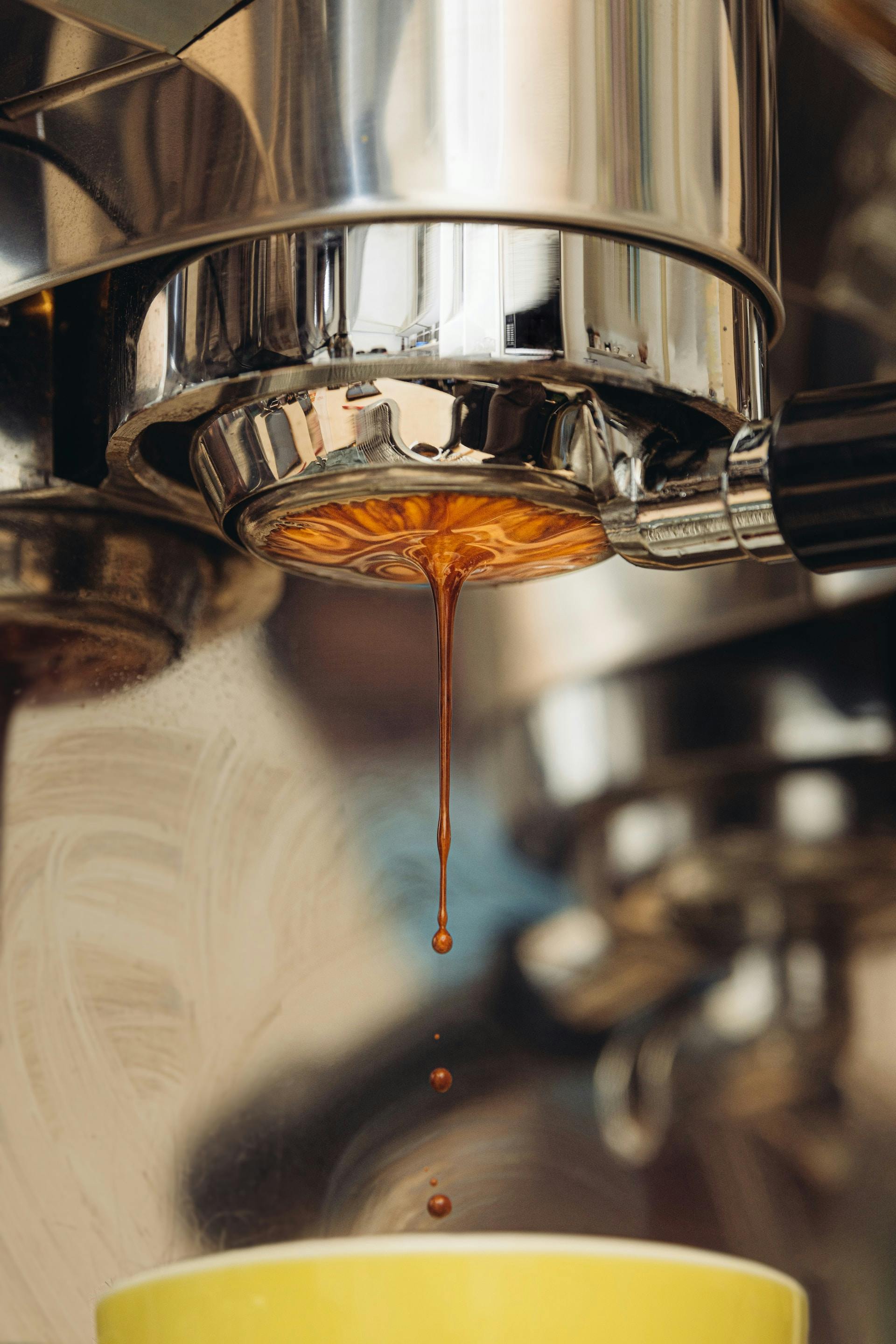 Aus Siebträgermaschine läuft braune Flüssigkeit in Kaffeetasse