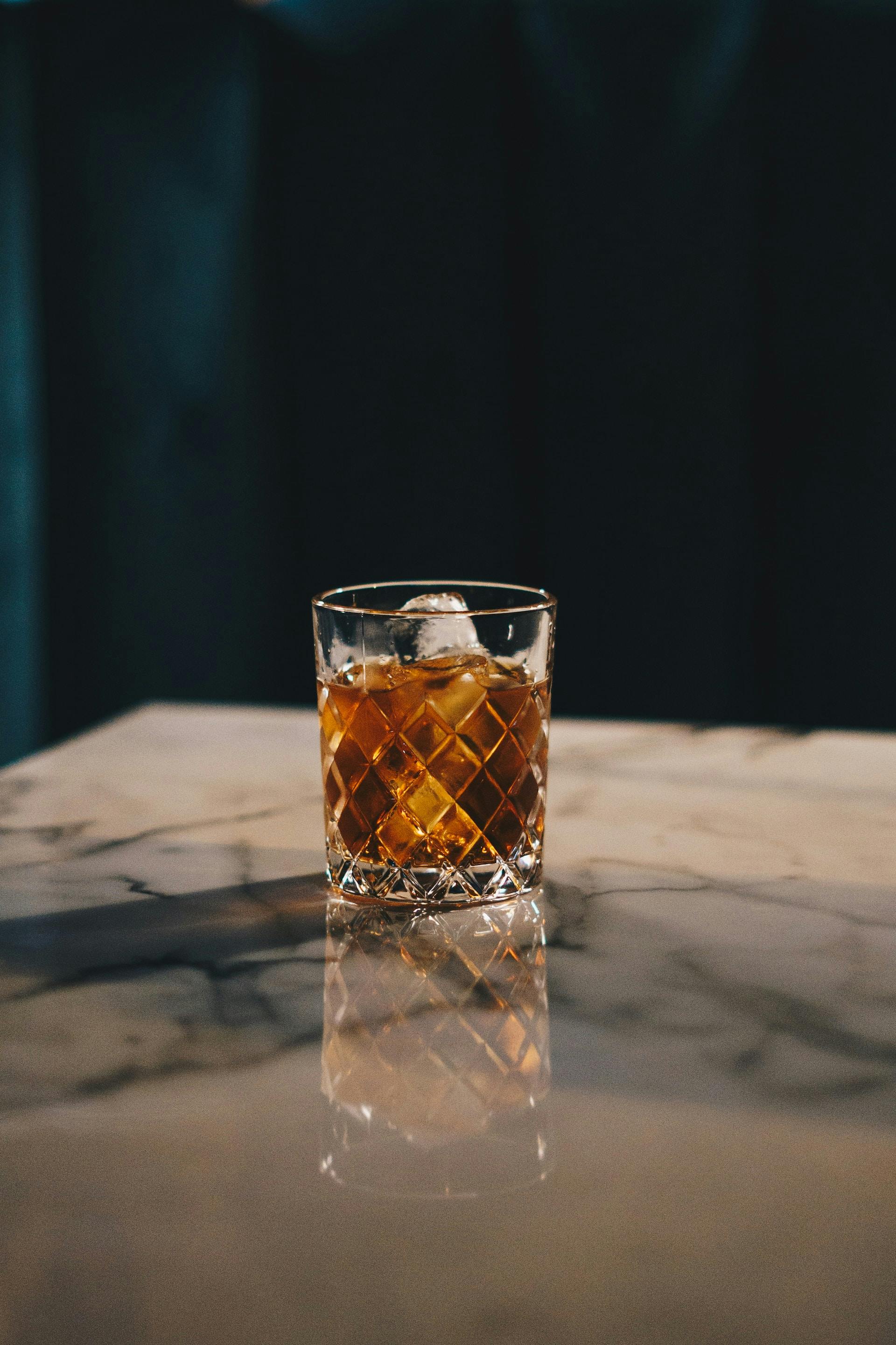 Kleines Whisky Glas mit brauner Flüssigkeit und Zitronenscheibe 