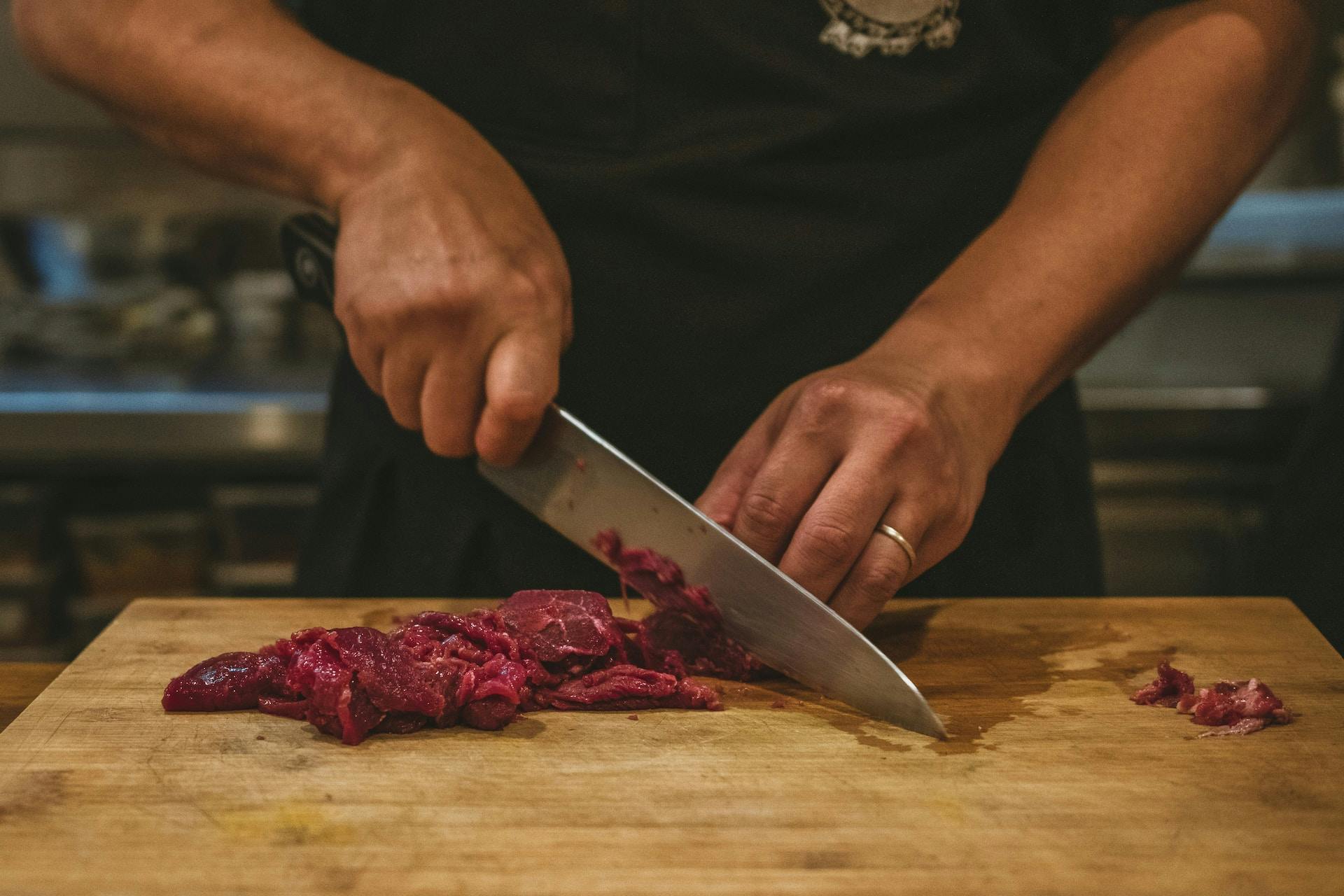 Mit Messer wird Fleisch geschnitten