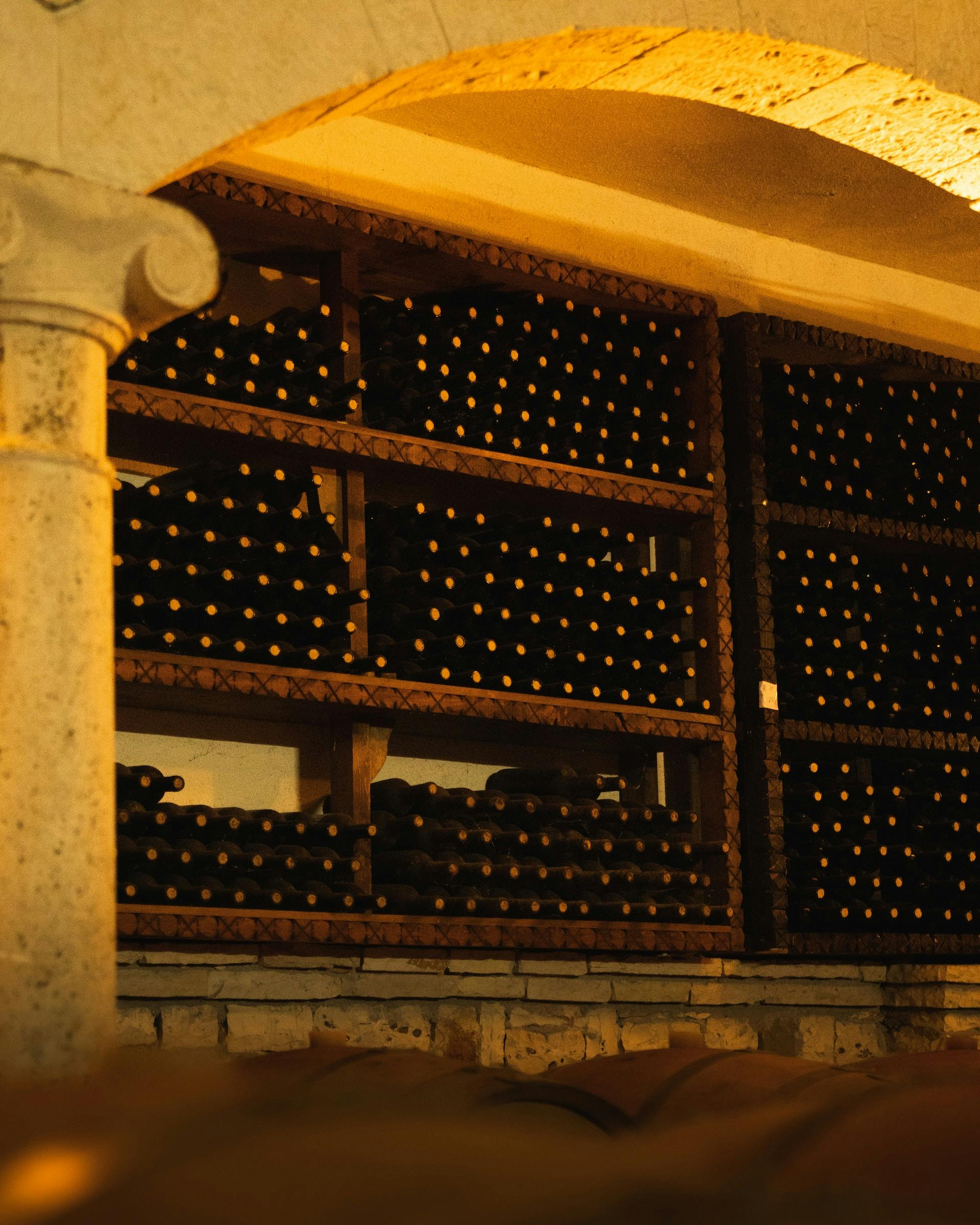In einem Gewölbe hohe Holzregale mit Weinflaschen