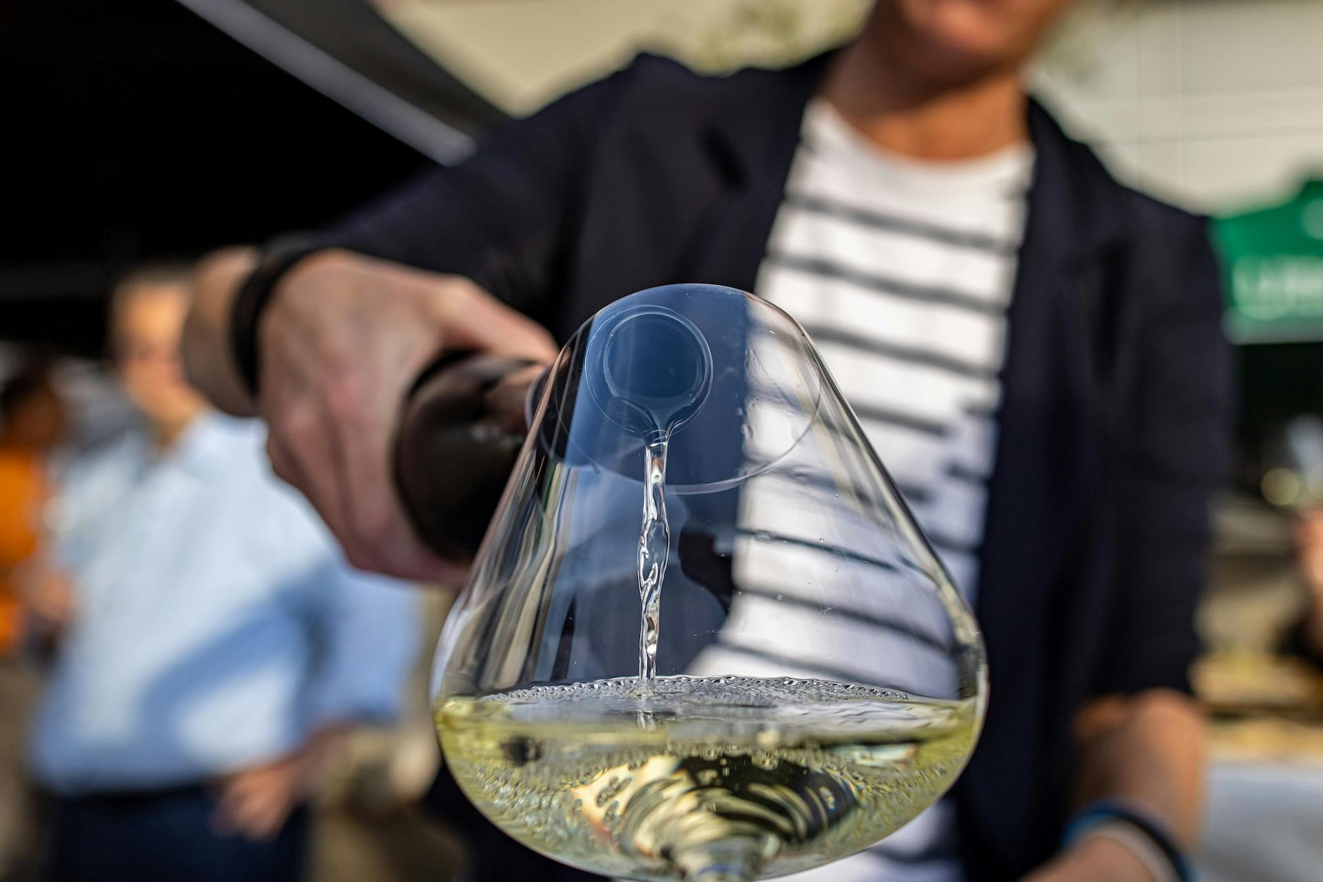 Eine Person gießt Weißwein ins Glas