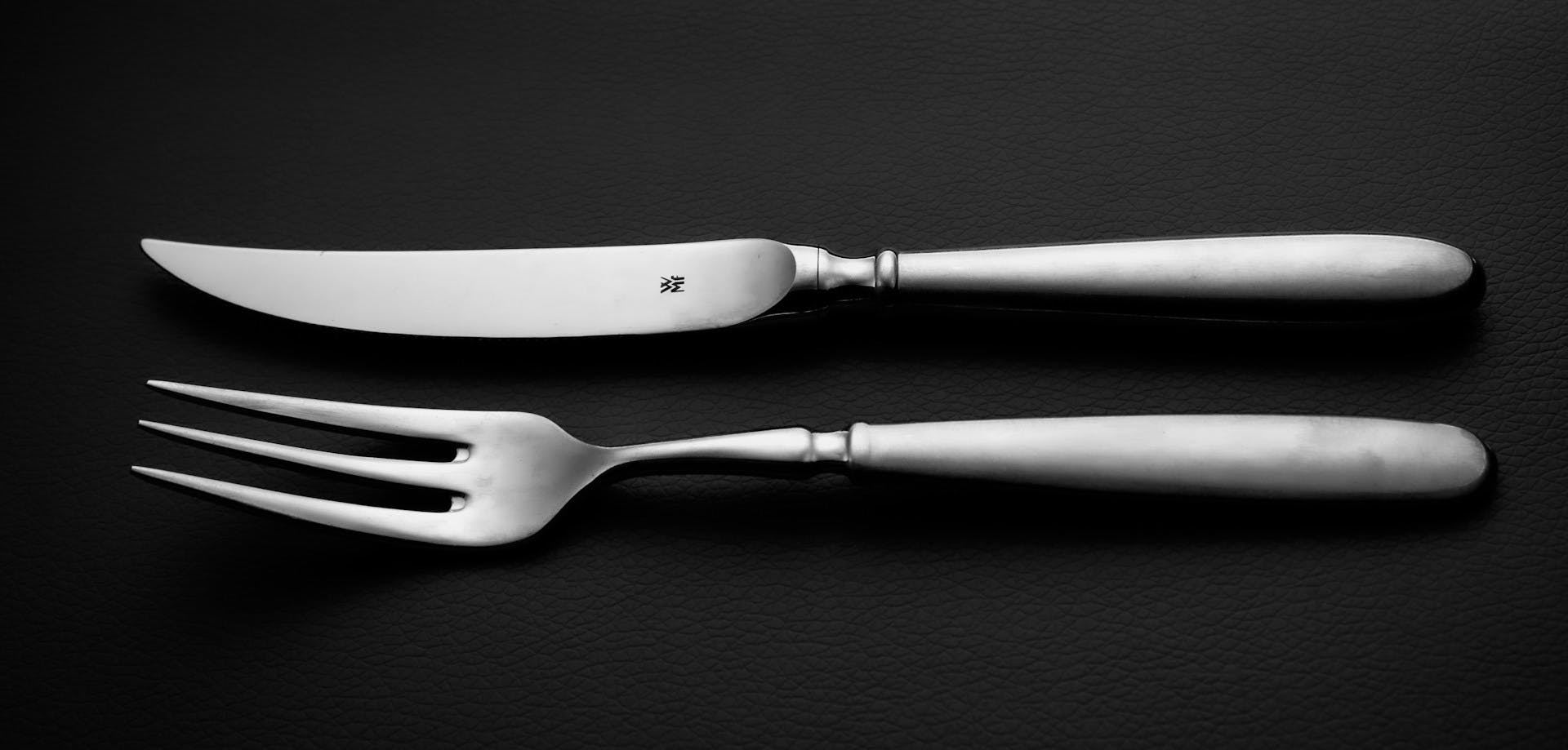 Messer und Gabel auf schwarzem Hintergrund