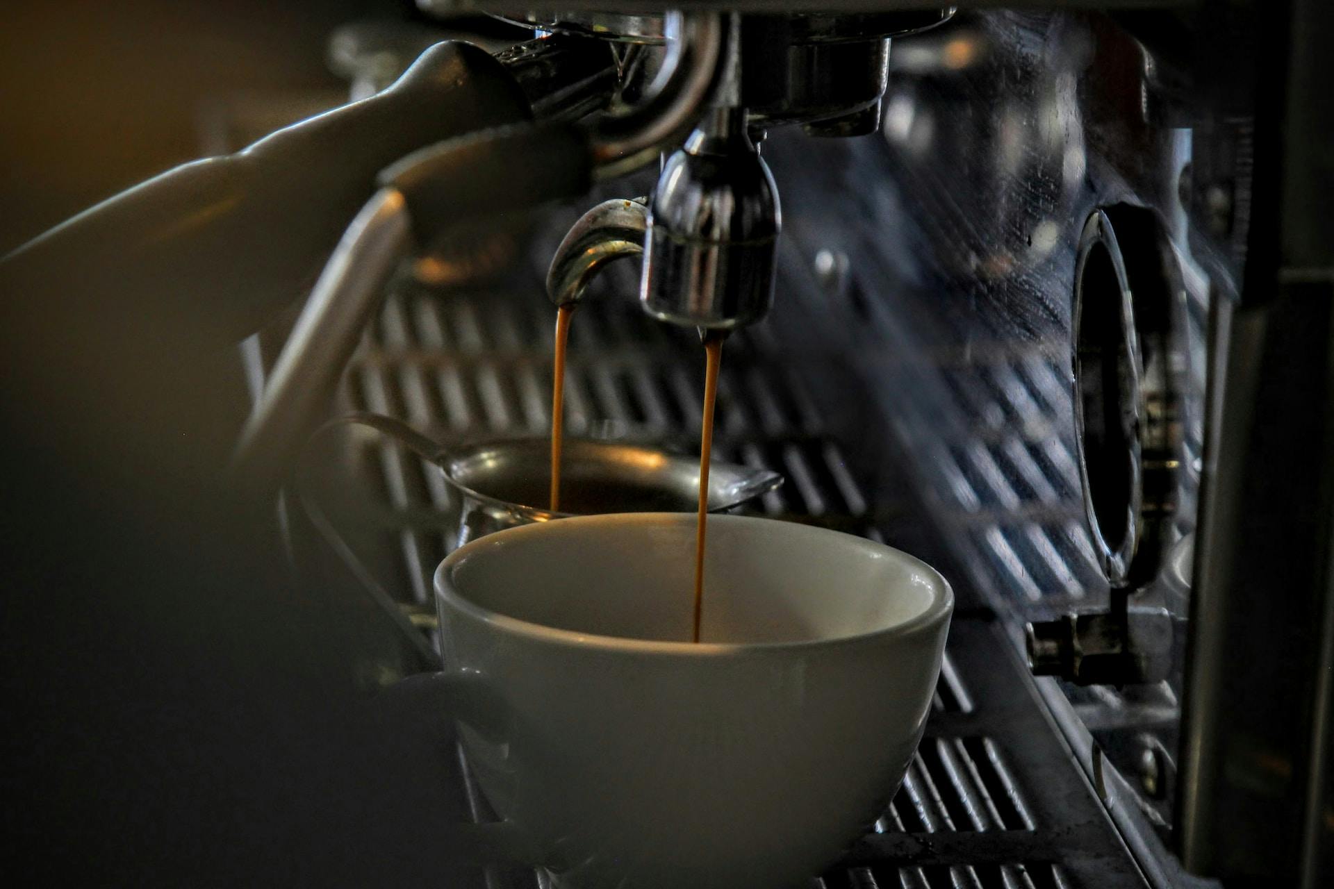 Braune Flüssigkeit wird von Kaffeemaschine in eine Tasse gefüllt